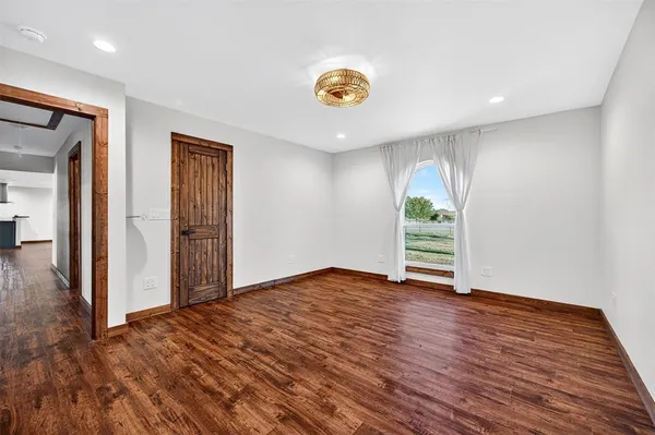 a view of an empty room with wooden floor and window