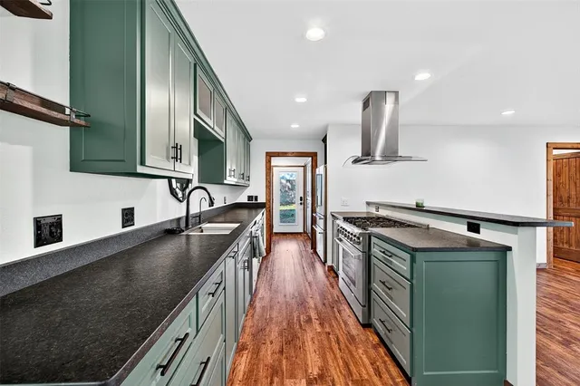 a kitchen with stainless steel appliances granite countertop a sink a stove and a wooden floors