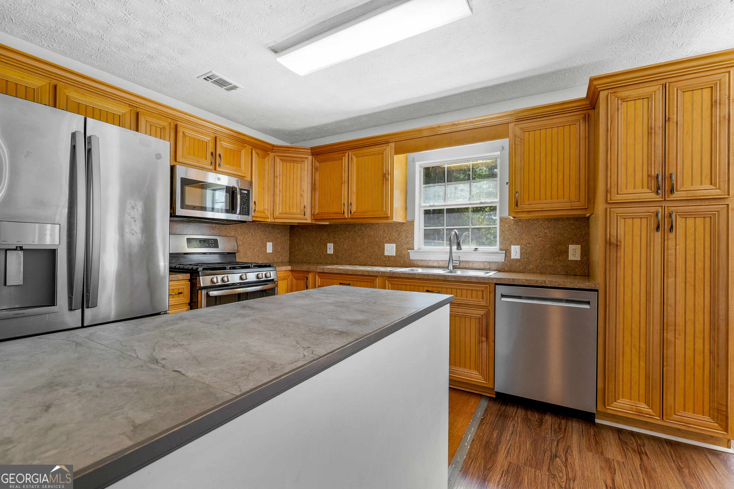 108 Nicki Court Hampton, GA 30228 - Photo 3 of 27 a kitchen with stainless steel appliances granite countertop a refrigerator a sink dishwasher a stove and wooden cabinets with wooden floor
