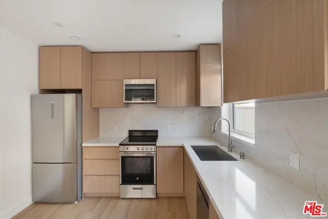 a kitchen with stainless steel appliances a sink stove and refrigerator