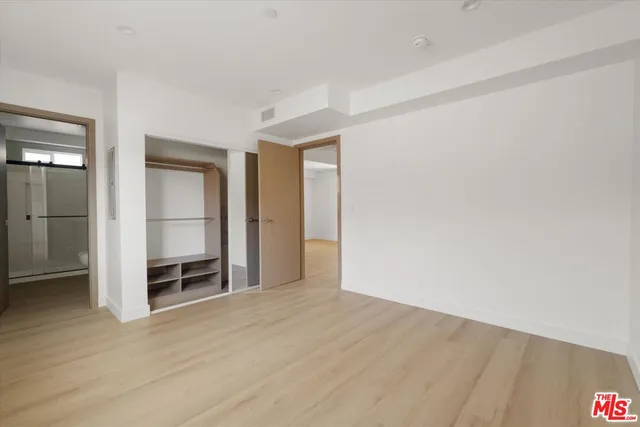 a view of an empty room with wooden floor and closet