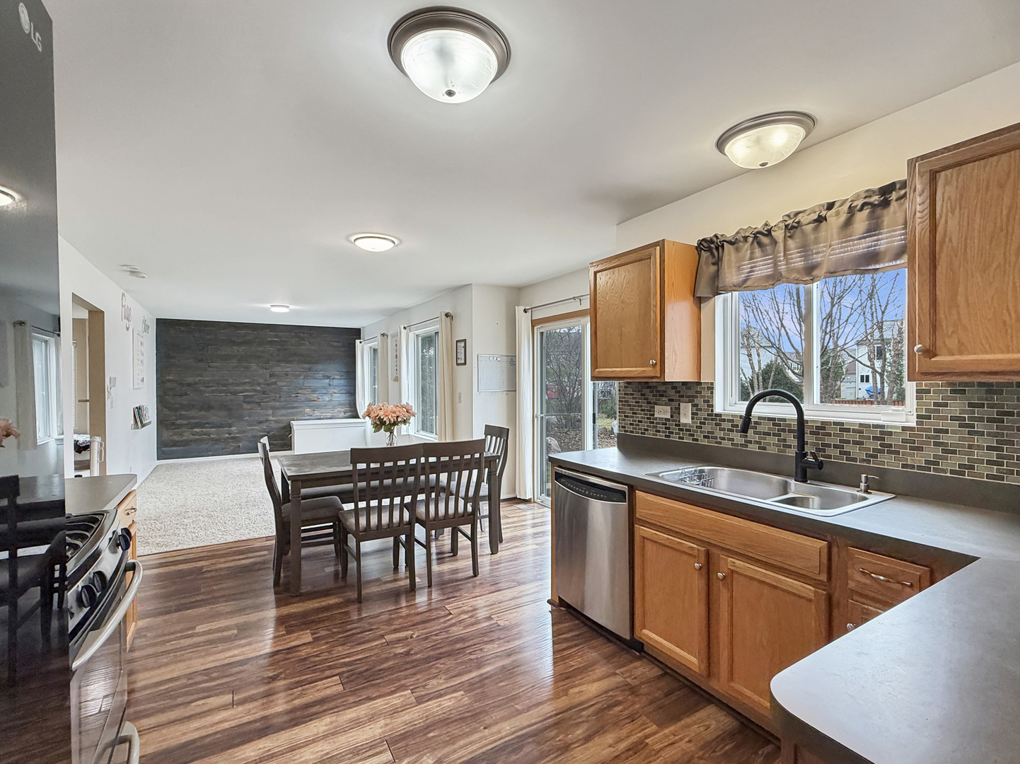 1114 Port Royal Road Pingree Grove, IL 60140 - Photo 9 of 25 a kitchen with stainless steel appliances granite countertop a sink dishwasher cabinets a dining table and chairs with wooden floor
