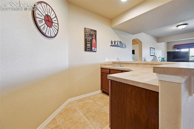 1918 Bashley Road Monument, CO 80132 - Photo 35 of 48 Kitchen with a peninsula, light tile patterned floors, arched walkways, light countertops, and brown cabinets