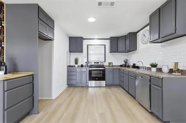 a kitchen with stainless steel appliances a sink dishwasher stove refrigerator and cabinets