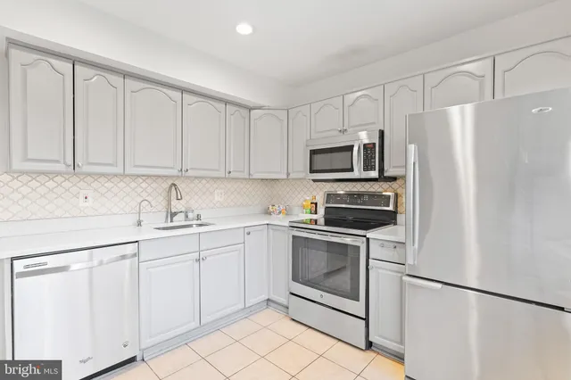 a kitchen with white cabinets sink and stainless steel appliances