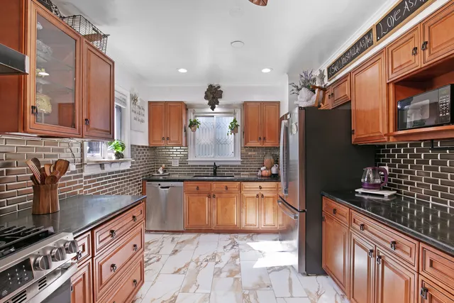 a kitchen with stainless steel appliances granite countertop a refrigerator a sink dishwasher stove and oven
