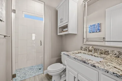 a bathroom with a granite countertop sink a mirror and a toilet