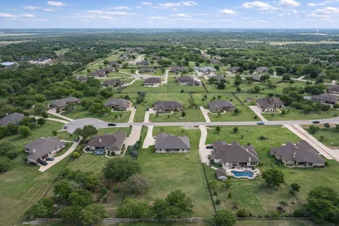 an aerial view of residential houses with outdoor space and trees