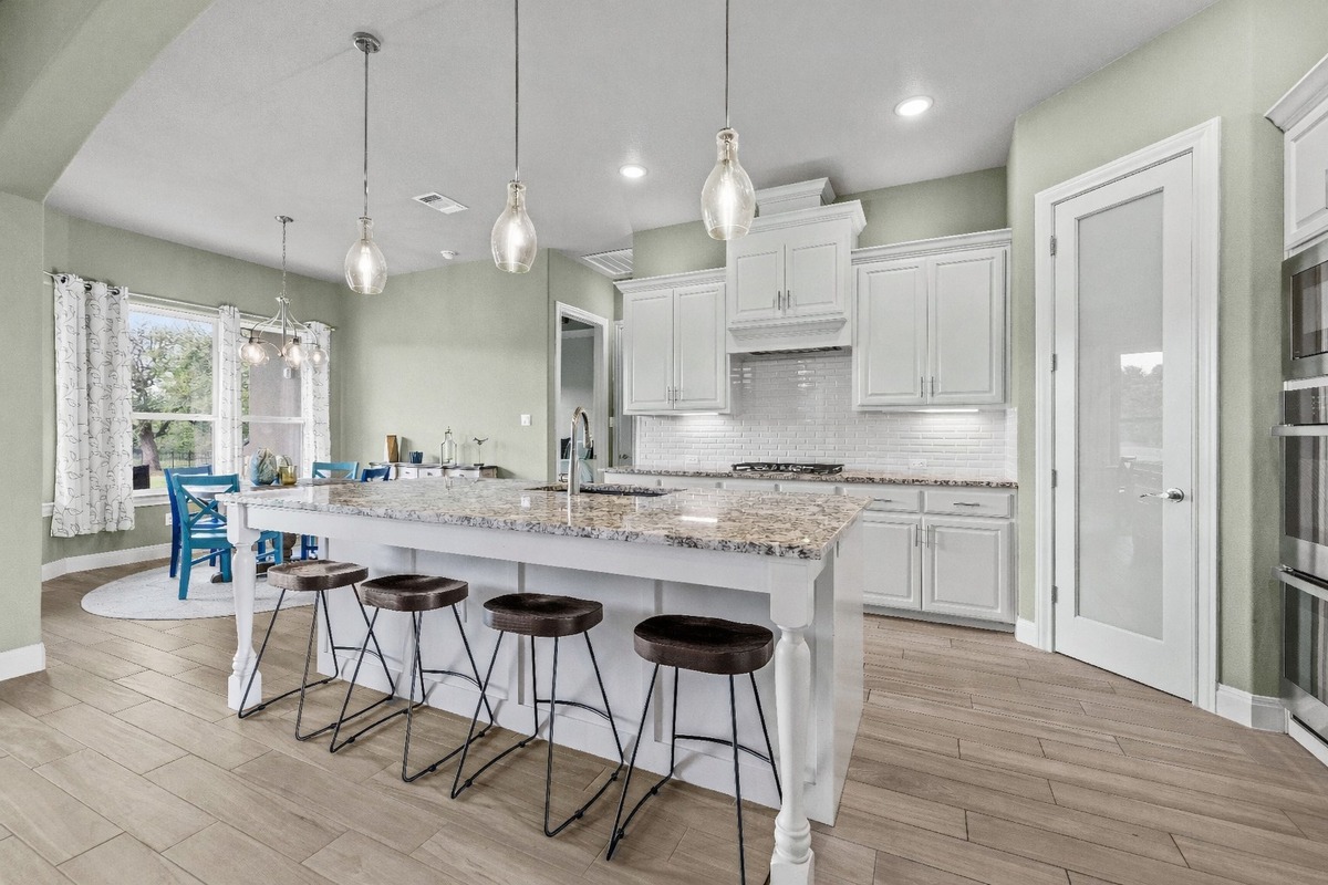 329 Independence Drive Georgetown, TX 78633 - Photo 6 of 34 a kitchen with stainless steel appliances granite countertop a stove a sink a kitchen island and chairs with wooden floor