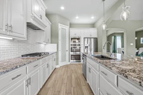 a large kitchen with granite countertop a lot of counter space and wooden floor