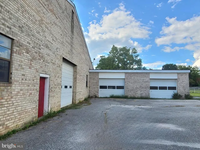 a view of a white house next to a yard and road