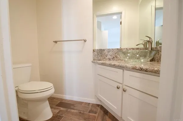 a bathroom with a granite countertop sink and a toilet