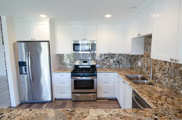 a kitchen with stainless steel appliances granite countertop a refrigerator and a sink