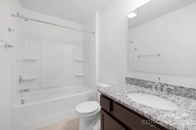a bathroom with a granite countertop sink a toilet and bathtub