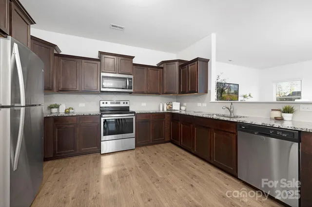 a kitchen with granite countertop a refrigerator stove top oven and sink