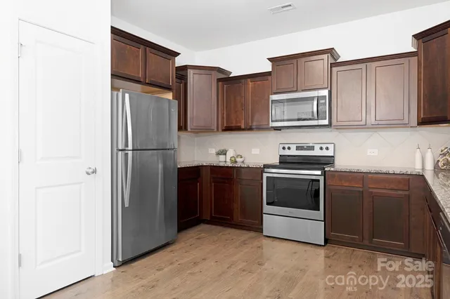 a kitchen with stainless steel appliances granite countertop a refrigerator stove and a sink