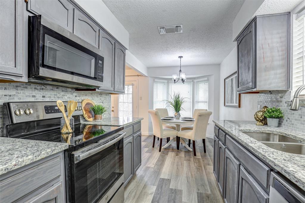 6005 Oak Hill Road Watauga, TX 76148 - Photo 11 of 22 a kitchen with stainless steel appliances granite countertop a sink stove and microwave