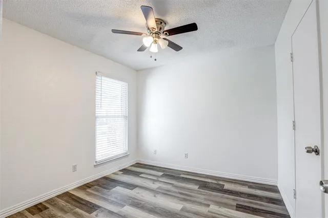 an empty room with windows and fan