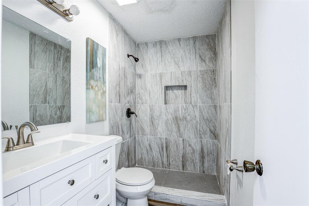 6005 Oak Hill Road Watauga, TX 76148 - Photo 19 of 22 a bathroom with a shower sink vanity mirror and toilet
