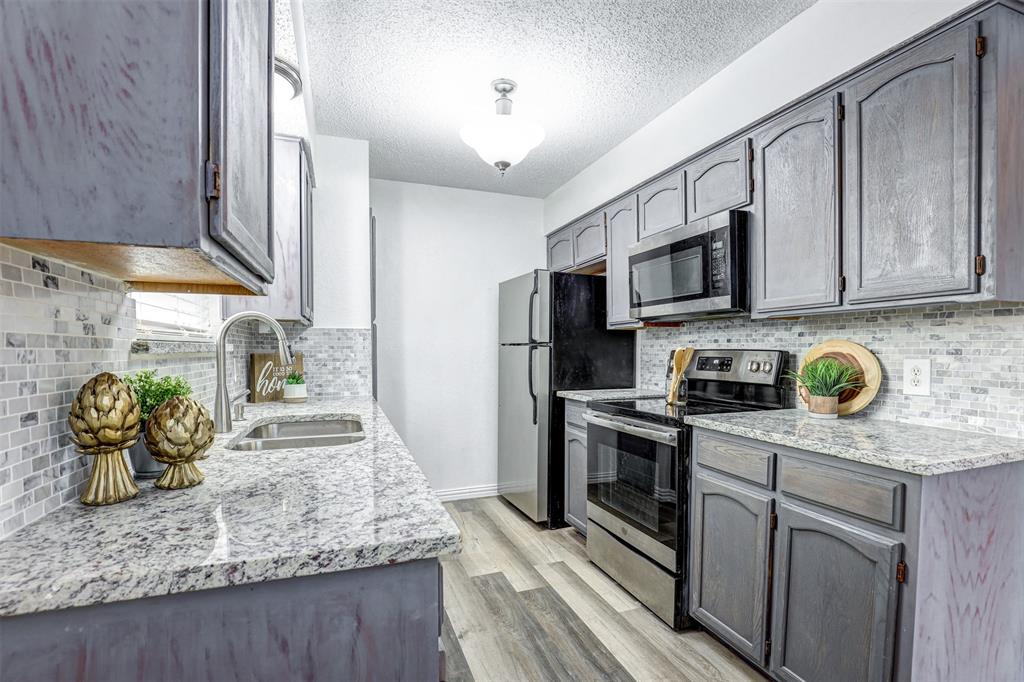 6005 Oak Hill Road Watauga, TX 76148 - Photo 9 of 22 a kitchen with stainless steel appliances granite countertop a sink a stove top oven a granite counter tops and a view of living room