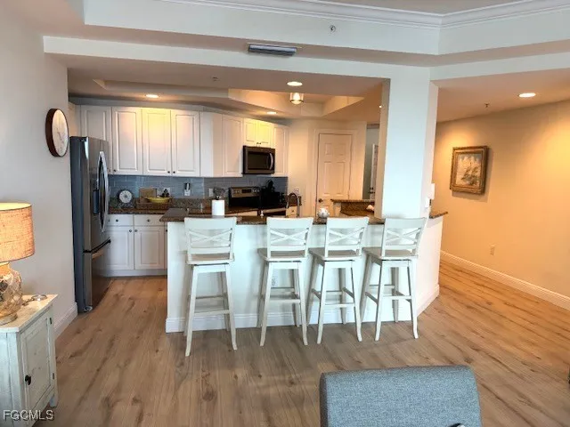 a kitchen with stainless steel appliances kitchen island granite countertop a table chairs and a refrigerator