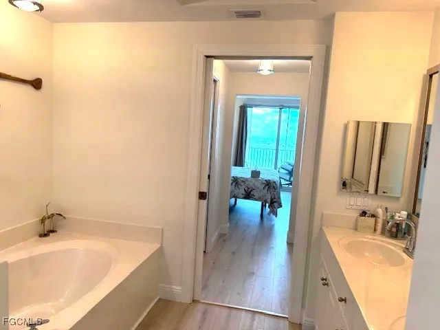 a bathroom with a tub a sink and mirror