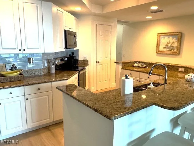 a kitchen with granite countertop a sink a stove and cabinets