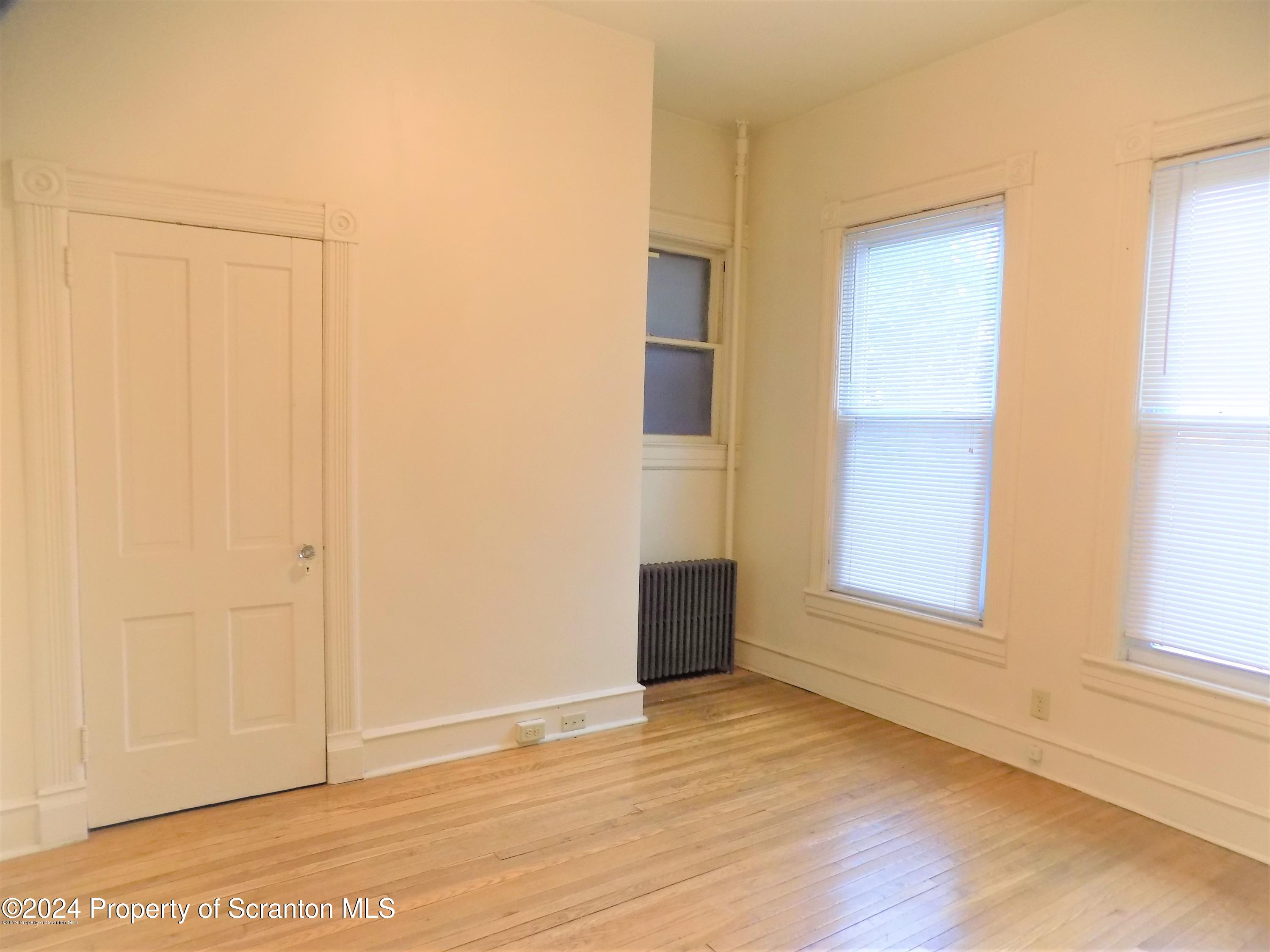 1543 Sanderson Avenue, Unit 1B Scranton, PA 18509 - Photo 6 of 12 a view of an empty room with wooden floor and a window