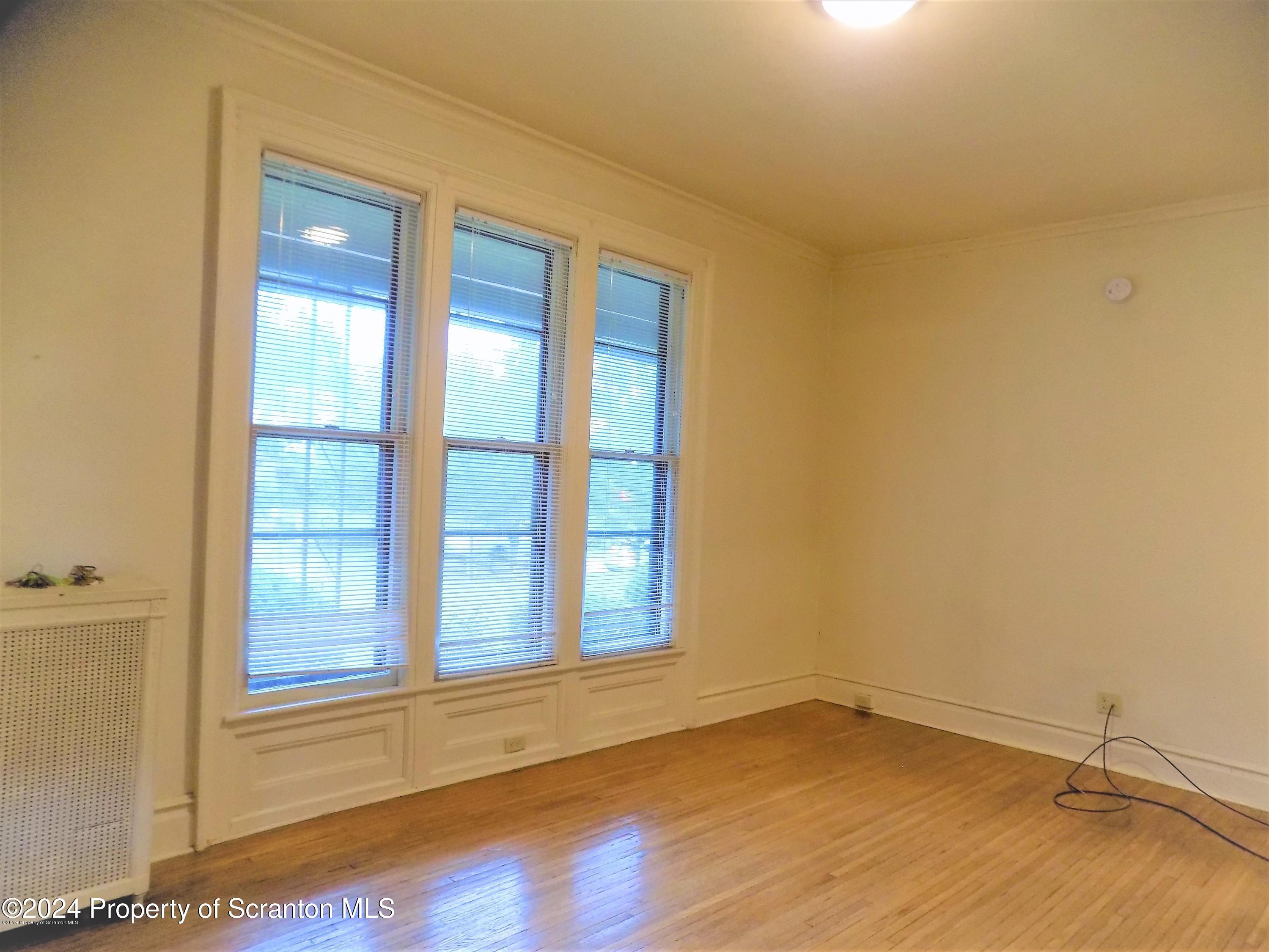 1543 Sanderson Avenue, Unit 1B Scranton, PA 18509 - Photo 8 of 12 a view of an empty room with wooden floor and a window