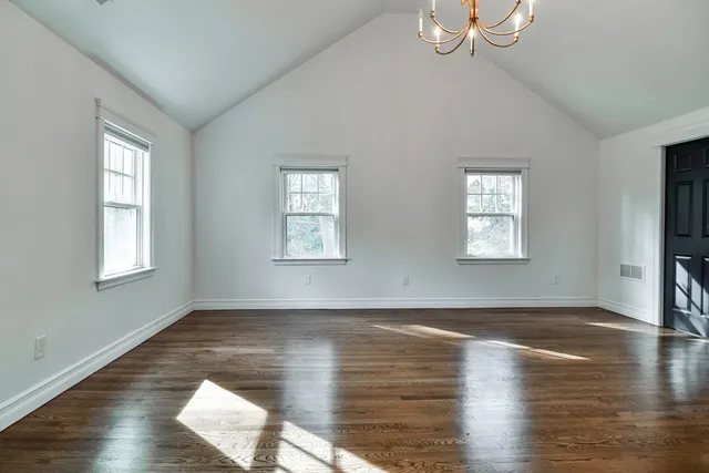 an empty room with wooden floor fireplace and windows