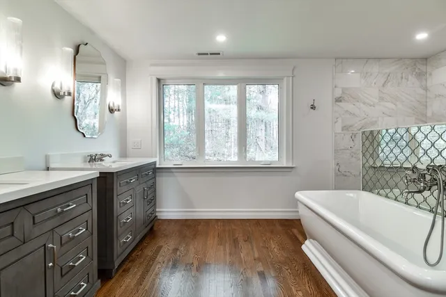 a white bath tub sitting in a bathroom next to a window