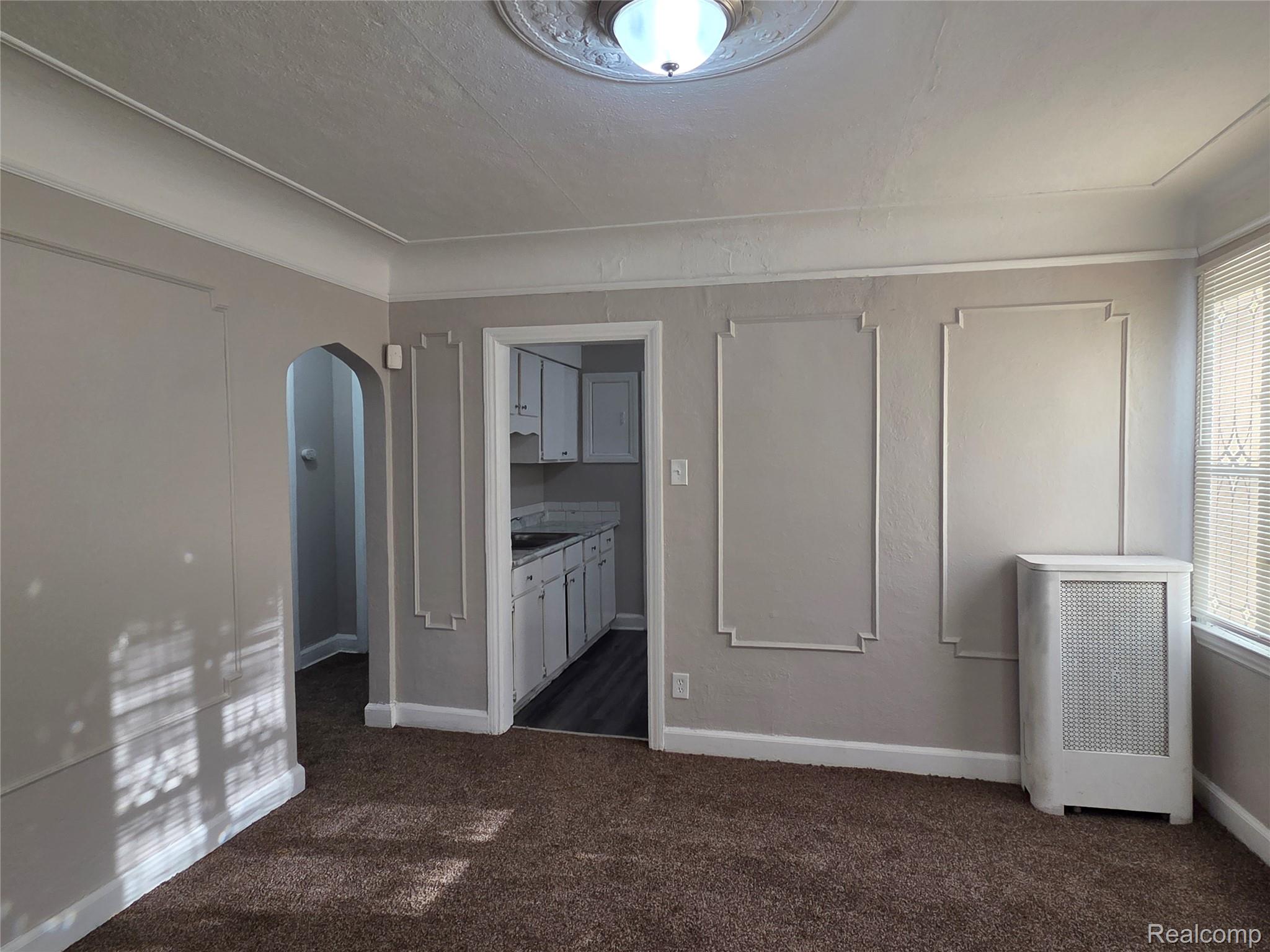 5274 Nottingham Road Detroit, MI 48224 - Photo 5 of 18 Unfurnished bedroom with arched walkways, radiator heating unit, and dark colored carpet