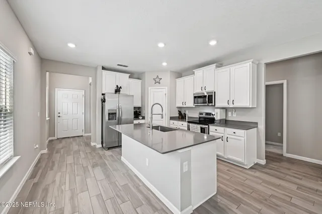 a kitchen with white cabinets and stainless steel appliances