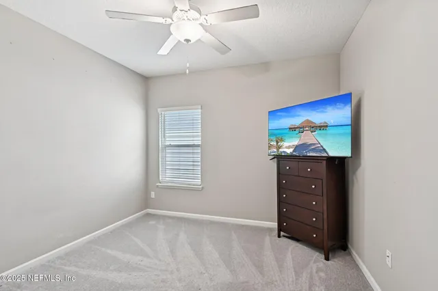 an empty room with windows and chandelier fan