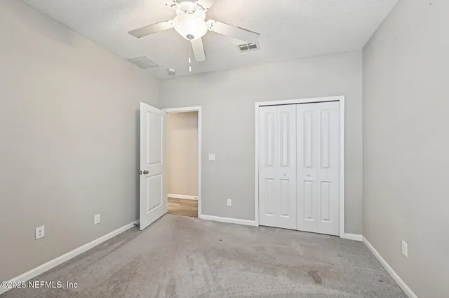 an empty room with a chandelier fan and a ceiling fan