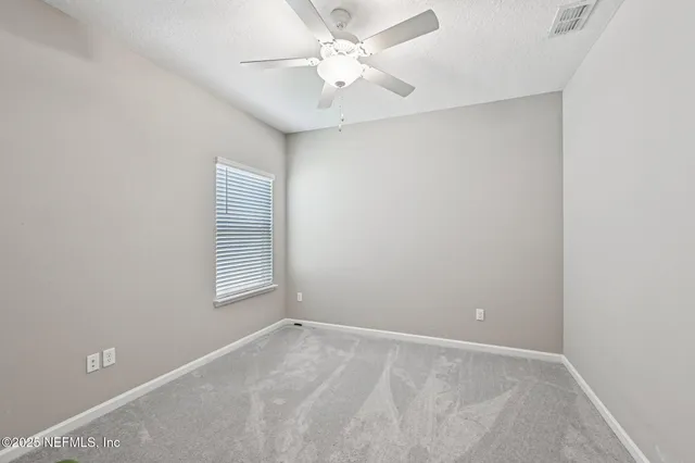 an empty room with windows and fan