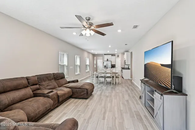 a living room with furniture a ceiling fan and a flat screen tv