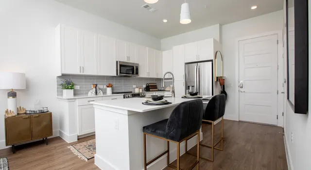 a kitchen with stainless steel appliances granite countertop a refrigerator a stove a sink a microwave and with wooden floor