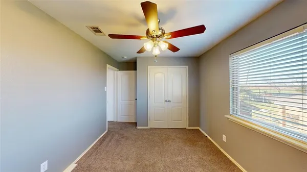 a view of an empty room with window and chandelier fan