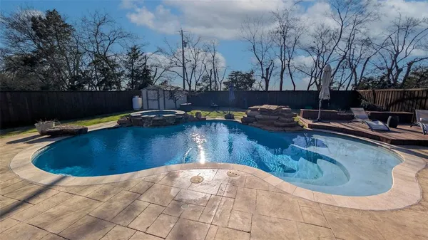 a view of a swimming pool with a yard and trees in the background