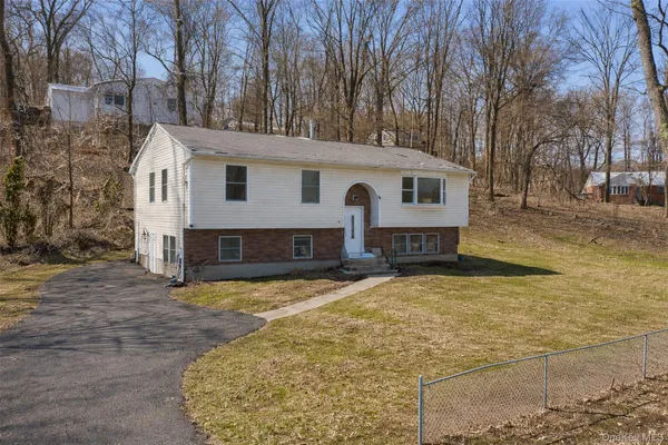 a view of a house with a yard covered with snow and trees