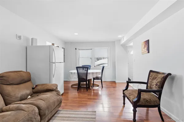 a living room with furniture a refrigerator and a dining table with wooden floor