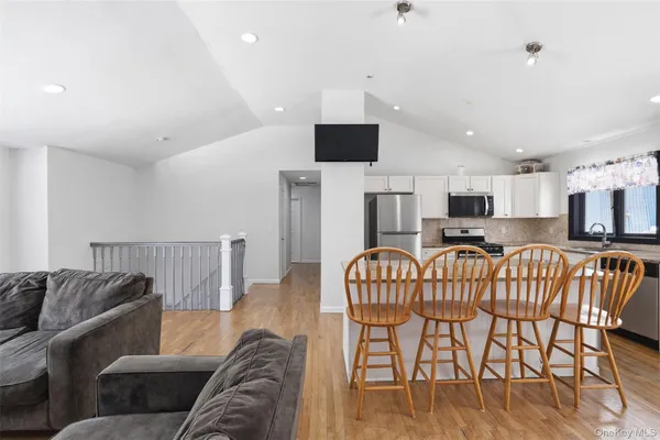 a living room with furniture a flat screen tv and kitchen view