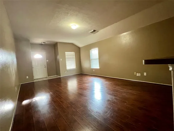 an empty room with wooden floor and windows