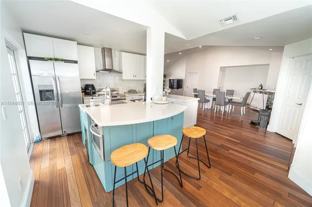 a kitchen with stainless steel appliances granite countertop a dining table chairs refrigerator sink and cabinets