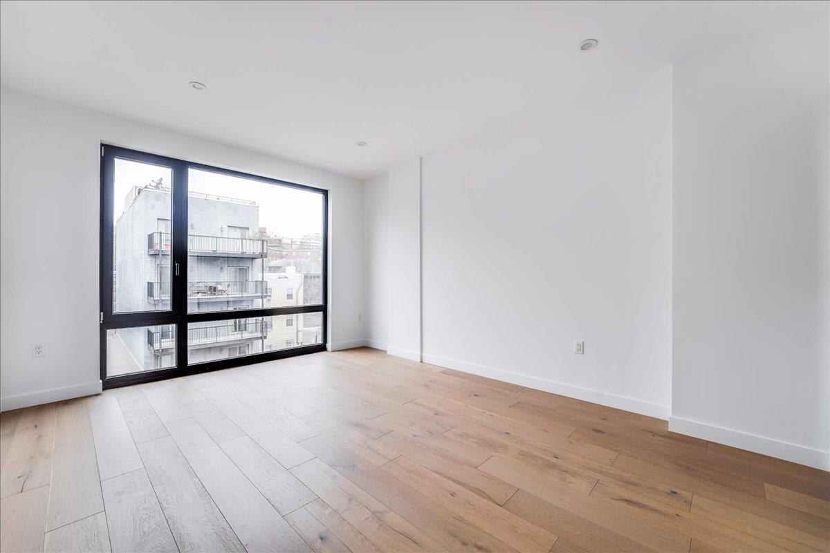 418 Monroe Street, Unit 201 Hoboken, NJ 07030 - Photo 11 of 29 a view of an empty room with wooden floor and a window