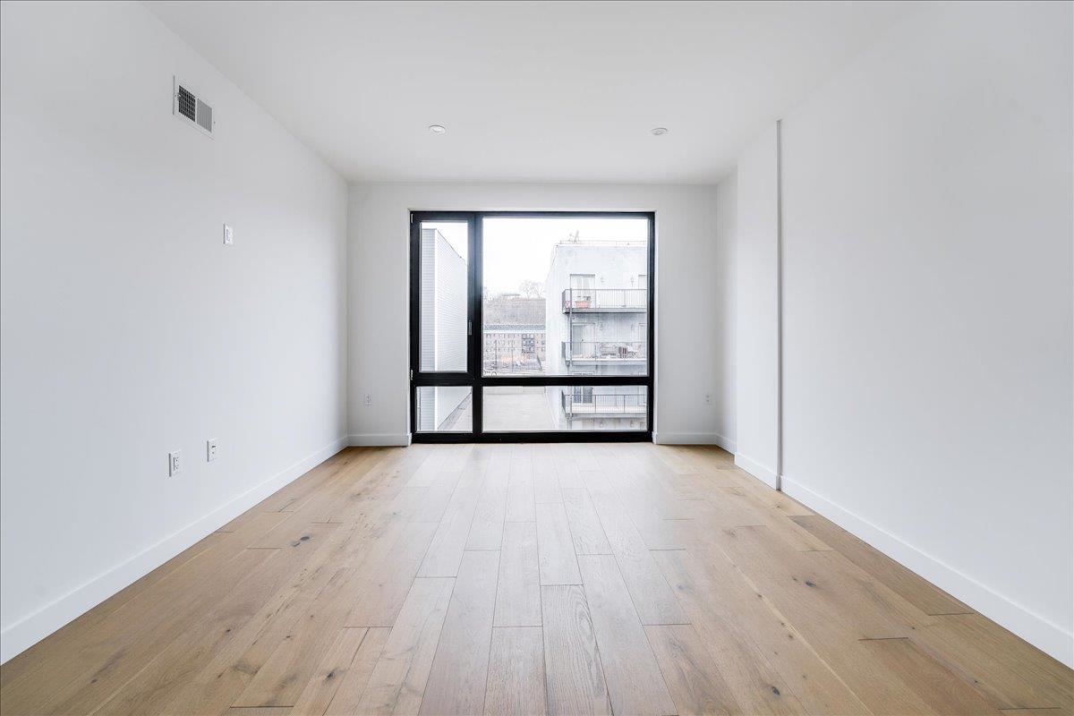 418 Monroe Street, Unit 201 Hoboken, NJ 07030 - Photo 12 of 29 wooden floor in an empty room with a window