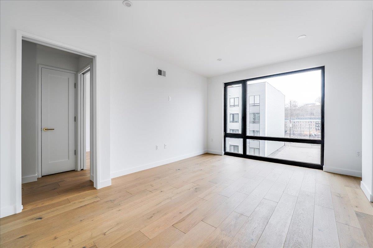 418 Monroe Street, Unit 201 Hoboken, NJ 07030 - Photo 13 of 29 a view of an empty room with wooden floor and sliding door