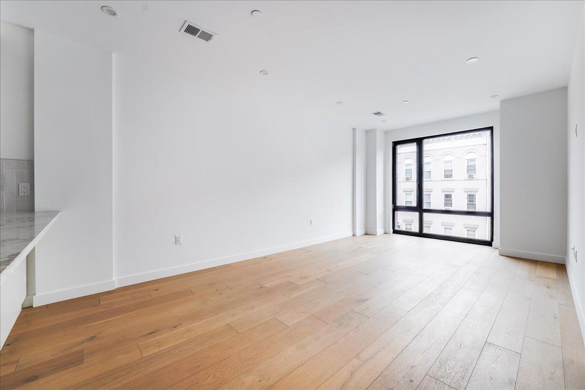 418 Monroe Street, Unit 201 Hoboken, NJ 07030 - Photo 6 of 29 wooden floor in an empty room with a window