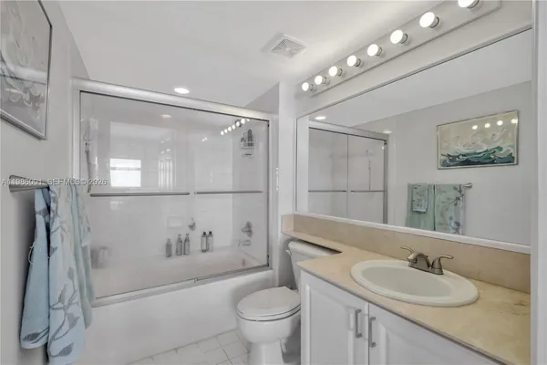 a bathroom with a granite countertop sink a toilet a mirror a vanity and shower